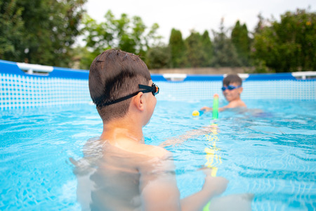 Little kids shooting with water gun outdoors