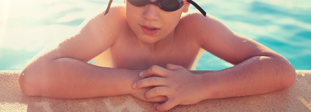 Little boy holding swimming pools edge, outdoors, closeupの写真素材