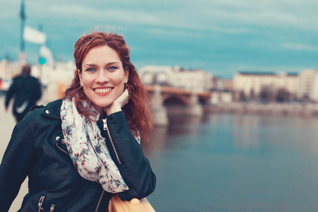 Happy young redhead carefree woman toothy smile on Margaret bridge in cold weather, Budapest, Hungaryの写真素材