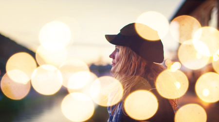 Young romantic urban woman daydreaming in city nightの写真素材