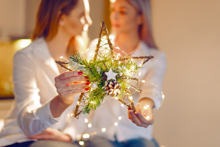 Young blonde lesbian couple holding Christmas star decoration at home, selective focus, depth of fieldの写真素材