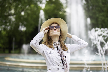 Happy young modern woman looking up in park at fountainの写真素材