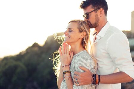 Young man holding blonde girlfriend in love by shoulder in natureの写真素材