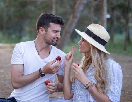 Happy young 20s couple joking during picnic in nature