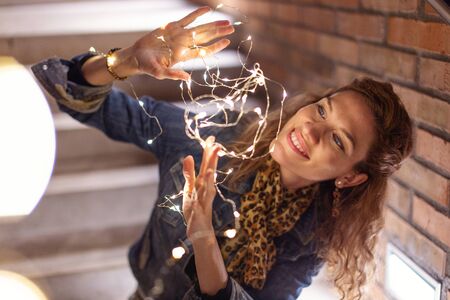 Redhead Caucasian woman playing with fairy lights outdoorsの写真素材