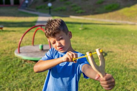 Little kid shooting with slingshot at playground outdoorsの写真素材