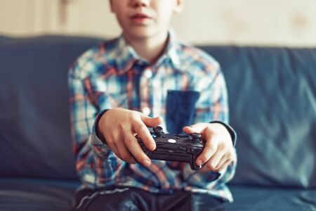 Young boy playing video game at home by controller, closeup