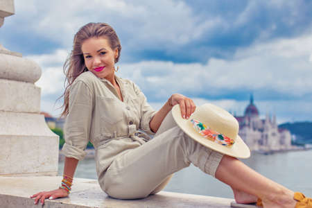 Young carefree woman sit on marble railing at Margaret Bridge, Budapest panorama, Hungaryの写真素材