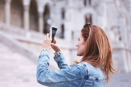 Young redhead tourist woman photographing the monuments in city, famous place, travelの写真素材