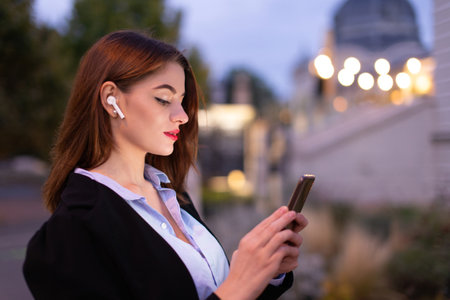 Young 20s Caucasian woman reading message on smartphone at eveningの写真素材