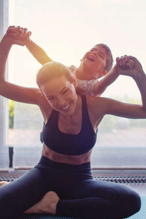 Woman silhouette doing yoga with son at home in sunsetの写真素材