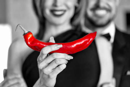 Healthy sexual life, woman holding chili pepper with happy male black and white with red conceptの写真素材