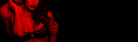 Sensual brunette woman in underwear with young lover in red light, passionate couple foreplay closeupの写真素材