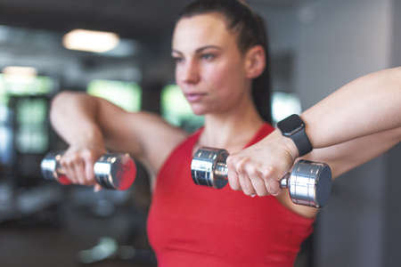Young woman doing exercise with dumbbells portrait, depth of field