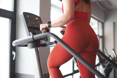 Woman body in sportswear workout on treadmill closeup