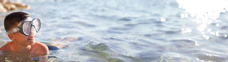 Happy Caucasian young boy with goggles in sea widescreen banner
