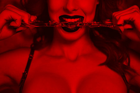 Sexy woman bite handcuffs closeup, black and white selective coloring with red, bdsmの写真素材