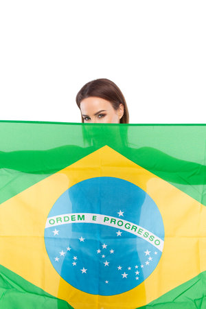 Young woman hiding her body and face by Brazil flag isolated on whiteの写真素材