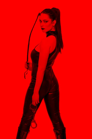 Sexy woman in latex catsuit and whip looking back in red light, bdsm.の写真素材