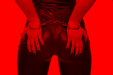 Sexy dominatrix hands on ass in handcuffs in red light, BDSM.の写真素材
