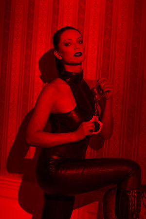 Sexy young woman in latex catsuit holding handcuffsの写真素材