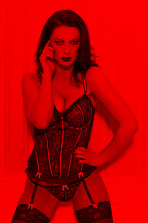 Sexy lover woman in vintage corset posing in red lightの写真素材