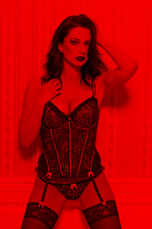 Sexy young dancer in vintage corset posing in red lightの写真素材