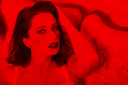Sexy young 20s Caucasian woman portrait in red light on sofaの写真素材