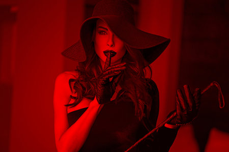 Sexy dominant woman in hat and whip showing no talk in red light, bdsmの写真素材