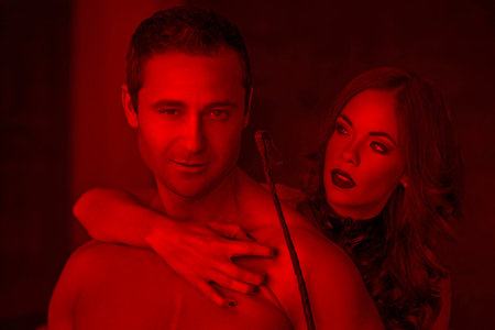 Sexy dominatrix claw young macho lover in red light, BDSMの写真素材