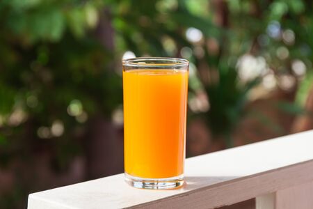 Glass of of orange juice with green leaf backgroundの写真素材