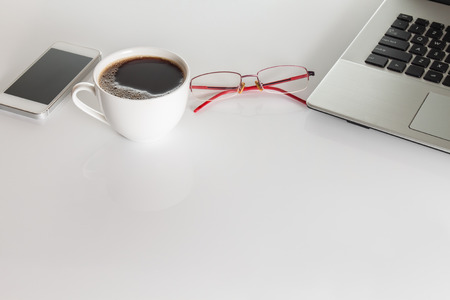 office interior with  laptop ,cup of coffee, glasses and  smartphone on white backgroundの写真素材