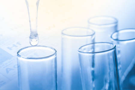 Laboratory pipette with drop of liquid over glass test tubes,in blue color styleの写真素材