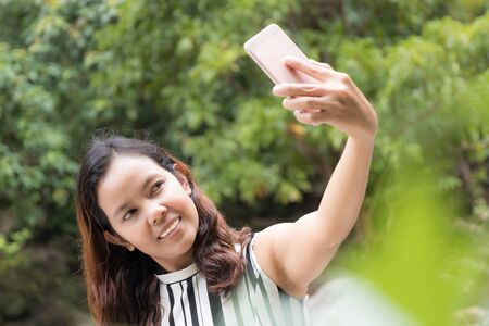 portrait of asian women  taking a selfie  of herself using smart phone cameraの写真素材