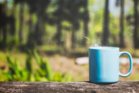Cup of coffee or tea on plank wood with green nature backgroundの写真素材