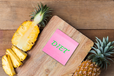 Pineapple slice on wood cut board with diet text on paper note, healthy conceptの写真素材