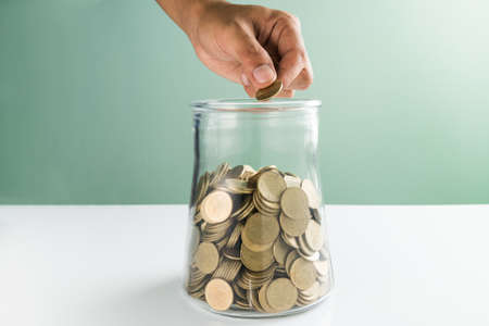 hand drops money into a glass bottle ,savings conceptの写真素材