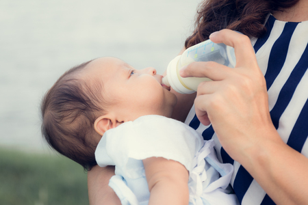 infant baby on being fed by her mother drinking milk from bottle.asian newbornの写真素材