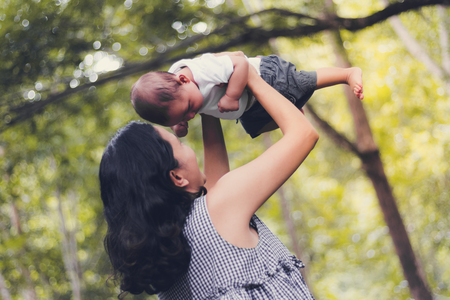 Happy baby play flying on mother hand in forestの写真素材
