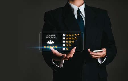 business man holding phone in customer satisfaction survey concept Users rate the service experience on the online application. Customers can assess the quality of service leading to business reputation rankings.の写真素材