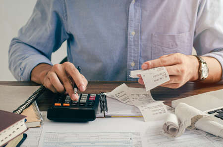 Male investors are calculating investment cost statistics with calculators and bills spent on hand.の写真素材