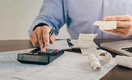 Male investors are calculating investment cost statistics with calculators and bills spent on hand.の写真素材