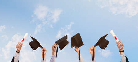 people who have been successful in education holding a graduation cap on the background of bright sky with beautyの写真素材