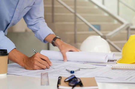 The engineer is drafting the planning structure. with architect equipment and architectural blueprints at the desk, coffeeの写真素材