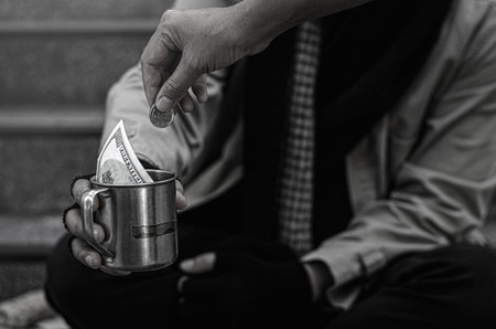 Close-up of the poor or homeless Homeless people ask for money in public. The poor beggar in the city sat on the stairs with a silver mug.の写真素材