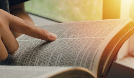 A young woman pointing out the verses of the Scriptures that are true to life. while reading the bible In the morning by the window sillの写真素材