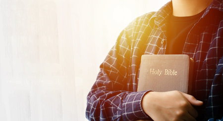 young woman hugging bible and praying to god faith forgivenessの写真素材