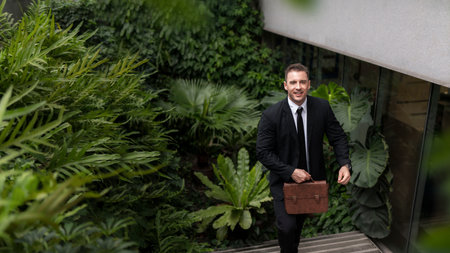 Businessman ceo manager walking up stairs amidst green buildings ESG concept of green business in sustainable development goals Green building Modern building in green city environmental friendlyの写真素材