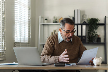 An elderly man celebrates while reviewing retirement savings documents and annual tax audit.の写真素材