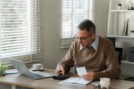 Retired old man is calculating stress about annual tax, debt, arrears in the house. Tax concept.の写真素材